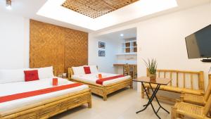 a room with two beds and a flat screen tv at RedDoorz @ DBuilders Ph1 Taguig in Manila
