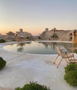 una piscina de agua con mesa y silla en Al Nyhaya, en Siwa