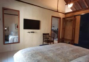 Un dormitorio con una cama y un televisor en la pared. en Refúgio Guest House, en Ilhabela