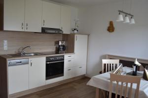 cocina con armarios blancos, fregadero y mesa en Appartementhaus Eberharter, en Hart im Zillertal