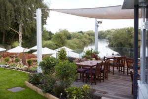 a deck with tables and chairs and a view of a river at Riverside Inn by Chef & Brewer Collection in Shrewsbury