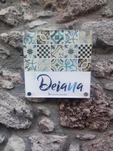 un cartello sul lato di un muro di mattoni con piastrelle di Deiana a Santu Lussurgiu
