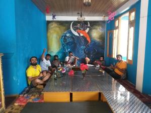 a group of people sitting around a table in a room at Snow View Guest House in Kasol
