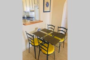 a dining room table with yellow chairs and a kitchen at Ático con terraza abierta/Open terrace apartment in Mijas