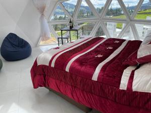 a bed in a room with a large window at Glamping Bosques del Neusa in Tausa Viejo