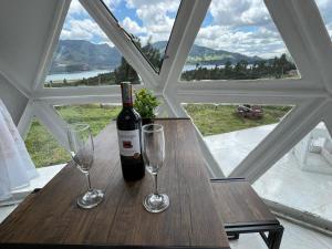 a bottle of wine sitting on a table with two glasses at Glamping Bosques del Neusa in Tausa Viejo