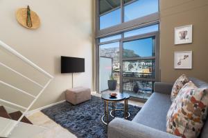 a living room with a couch and a table at City Slicker Double Volume Loft, Magnificent Table Mountain View, close to V&A Waterfront, never any load shedding! in Cape Town