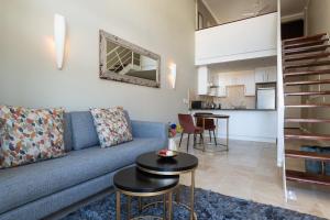 a living room with a blue couch and a table at City Slicker Double Volume Loft, Magnificent Table Mountain View, close to V&A Waterfront, never any load shedding! in Cape Town