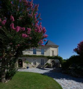 ein weißes Haus mit einem Baum mit rosa Blumen in der Unterkunft Domaine de Larchey in Saint-Médard-dʼEyrans