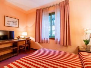 a hotel room with a bed and a desk and a window at Albergo Santa Barbara in Montecatini Terme