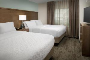 Cette chambre comprend deux lits et une télévision. dans l'établissement Staybridge Suites Greenville I-85 Woodruff Road, an IHG Hotel, à Greenville