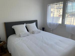 ein weißes Bett mit weißen Kissen und einem Fenster in der Unterkunft Ô Pure in Annecy