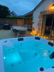 bañera de hidromasaje en una terraza con mesa y sillas en le penty plougonvelin, en Plougonvelin