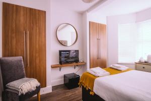 a bedroom with a bed and a mirror and a chair at Haven House Rooms, Barry in Barry