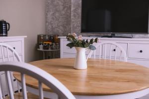 a dining room table with a vase with flowers on it at Haven House Rooms, Barry in Barry +28 photos