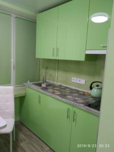 eine Küche mit grünen Schränken und einem Waschbecken in der Unterkunft Студія з сучасним ремонтом in Kiew