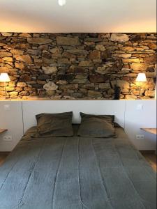 Cama en habitación con pared de piedra en le penty plougonvelin, en Plougonvelin