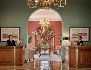 un uomo e una donna in piedi alla reception in una stanza di Château Saint-Martin & Spa - an Oetker Collection Hotel a Vence