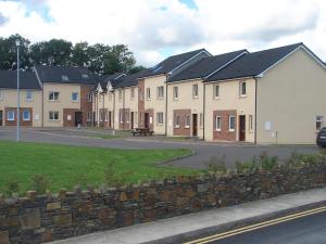 a row of houses with a stone wall at Coisceim Village in Tralee