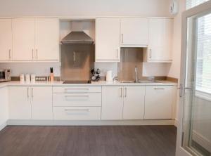 una cocina blanca con armarios blancos y fregadero en Valley View, en Harrogate