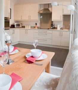 a kitchen with white cabinets and a wooden table with glasses at Valley View in Harrogate