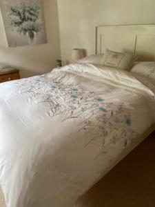 a bed with a white comforter with flowers on it at Prospect Cottage in Box