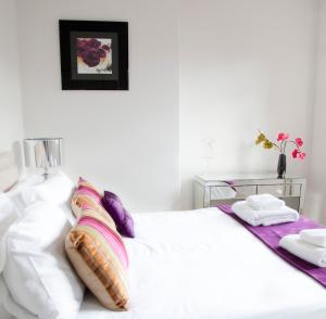 a white bedroom with a white bed with pillows at Valley View in Harrogate