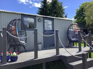 two chairs and a hammock on a wooden deck at The Shepherd s Hut at Hafoty Boeth in Corwen