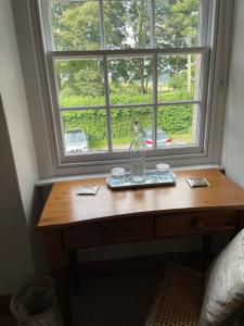 a table with a bottle on it in front of a window at Prospect Cottage in Box