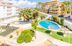 an apartment with a pool and palm trees and buildings at Nora Nice in Moraira