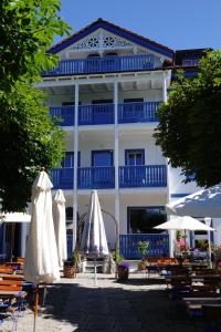 un bâtiment avec des tables et des parasols devant lui dans l'établissement Hotel-Gasthof Seehof Laax, à Laax