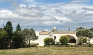 un edificio bianco con un arco in un cortile di Trulli Relais Casa Gemma a Martina Franca