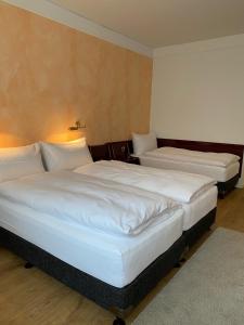 two beds in a hotel room with white sheets at Boutique City Hotel Gallo in St. Gallen
