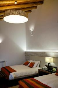a bedroom with two beds and a chandelier at Tocuyeros Boutique Hotel in Cusco