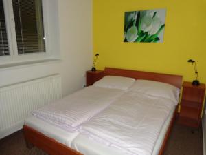 Una cama con sábanas blancas en una habitación con una pared amarilla. en Demänova 238, en Liptovský Mikuláš