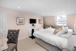 Argyle - Stunning 5 bed Luxury Home - Pulteney Bridge, Bath في باث: غرفة نوم بسرير وتلفزيون وكرسي