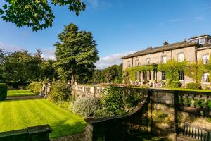 a house with a bridge in front of a garden at Doxford Hall Hotel And Spa in Chathill
