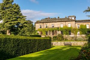 uma casa velha com uma sebe à frente. em Doxford Hall Hotel And Spa em Alnwick