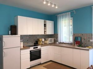 uma cozinha com armários brancos e uma parede azul em Szárszószép Villa em Balatonszárszó