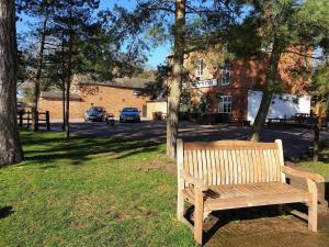 un banco de madera sentado en el césped junto a un árbol en The Cheney Arms en Gaddesby