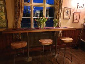 a bar with three stools in front of a window at The Cheney Arms in Gaddesby