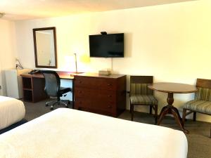 una camera d'albergo con scrivania, TV e letto di GuestLodge a West Dennis