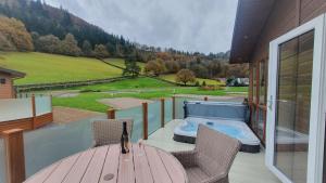 a balcony with a table and chairs and a hot tub at Llyn Alwen Lodge Snowdonia National Park in Betws-y-coed