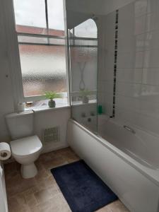 ein Bad mit einer Badewanne, einem WC und einem Fenster in der Unterkunft Sandyrise holiday lets in Scarborough