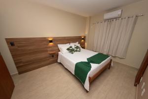 um quarto com uma grande cama branca e um cobertor verde em Terra D` Ouro Apart Hotel em São João del Rei