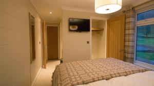 a bedroom with a bed and a television on the wall at Llyn Brenig Lodge in Betws-y-coed
