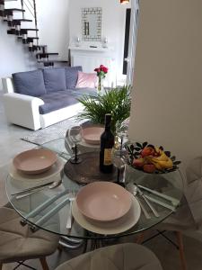 a glass table with plates and a bottle of wine at Apartament Kwiat Lotosu in Jelenia Góra