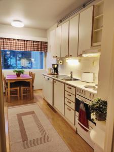 uma cozinha com armários brancos, uma mesa e um lavatório em Metsä Fibren biotehtaan lähellä (1,5km) 6 hlö:lle em Kemi