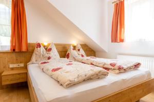2 Betten in einem Schlafzimmer mit orangefarbenen Vorhängen in der Unterkunft Pernerhof in Aich
