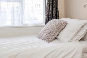 uma cama branca com duas almofadas em cima em TH Serviced Apartment London em Northolt